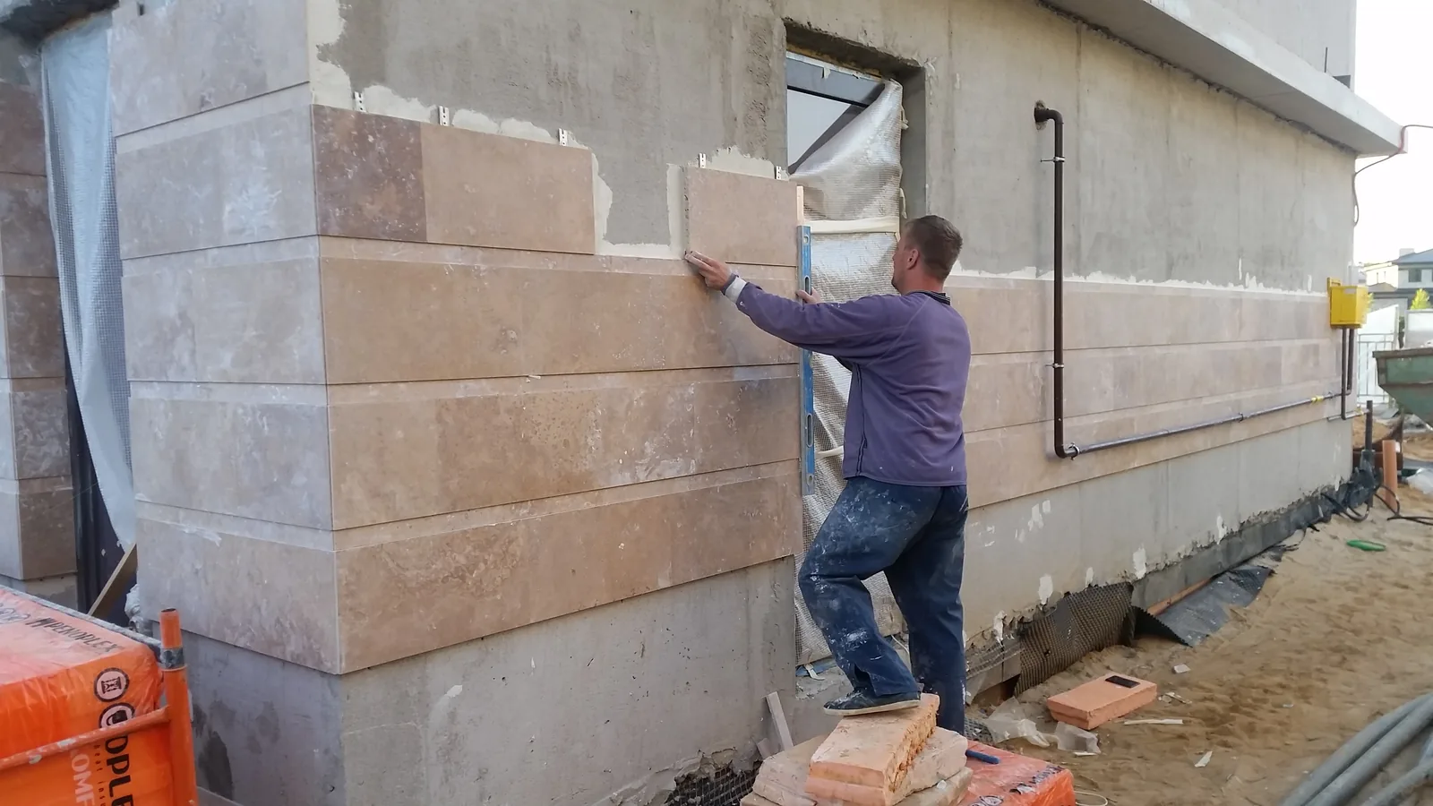 A craftsman cladding the façade in natural stone